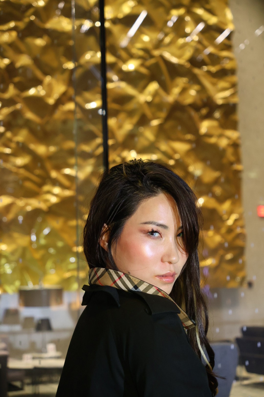 Enyu looking over her shoulder in a black coat