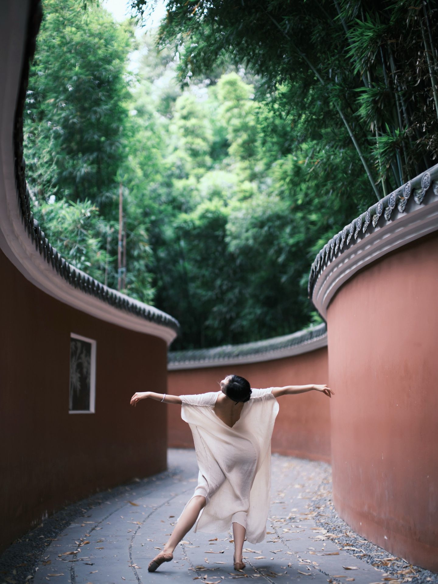 Dancer in white between curved garden walls